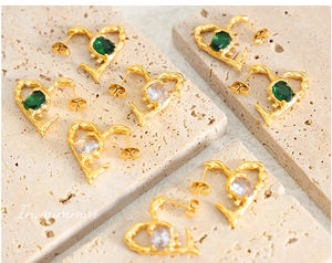 Detail of gold lava texture earrings featuring emerald and clear oval gemstones
