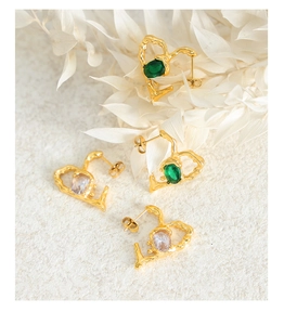 Detail of gold hammered heart earrings with green and white oval crystals on white background