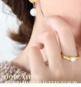 Detail of 18K gold earrings and ring set with blue beads and pearls on a model