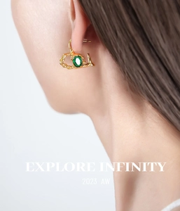 Detailed close-up of heart-shaped green glass stone earrings with gold lava texture