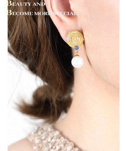 Detail of vintage 18K gold plated earring with blue bead and white pearl drop on model