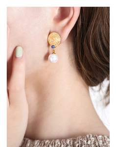 Detail of vintage French gold earrings with blue bead and large white pearl pendant