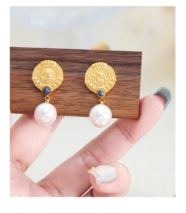 Detail view of 18K gold plated earrings with blue stone inlay and white pearl drops