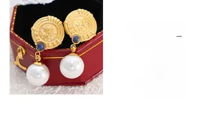 Detail of vintage gold coin earrings with blue stone and white large pearl pendants