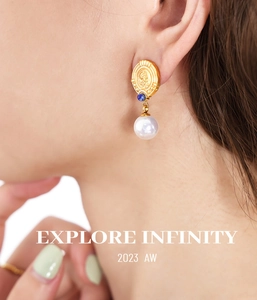 Close-up of vintage gold coin earrings with blue bead and round pearl on female model