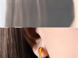 Detail of gold hoop earrings with star pattern engraving and micro zircon inlay