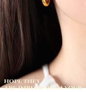 Close-up of a 18K gold plated hoop earring with a small zircon on a model ear
