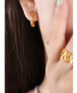 Detail of 18k gold earrings with star engraving and a multi-layer infinity ring