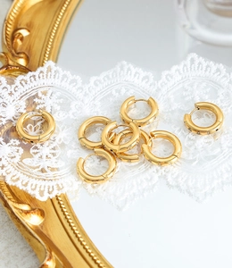 Macro detail of 18K gold-plated hoop earrings with micro-pave zircons on lace
