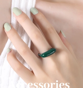 Gros plan d'une bague géométrique vert foncé brillant sur le doigt d'un mannequin