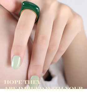 Gros plan d'une large bague dorée vintage avec émail vert foncé sur le doigt d'un mannequin