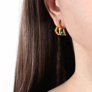 Lava texture gold earrings with marquise emerald green stone worn by a female model