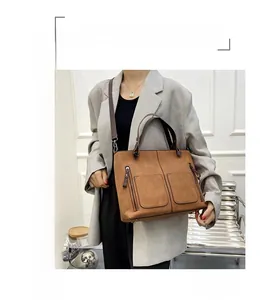 Detailed view of brown matte leather tote bag with dual front pockets and shoulder straps