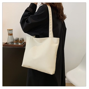 Close-up of cream large tote bag showing soft lychee leather texture and minimalist handle
