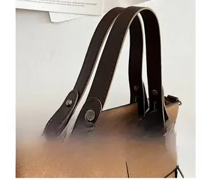 Detail of brown matte suede handbag with leather handles and reinforced stitching