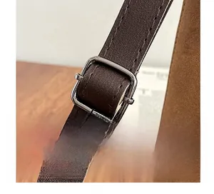 Detailed macro view of deep brown pebbled leather shoulder strap with silver buckle