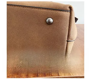 Close-up of durable metal rivets on the bottom of a brown faux suede handbag