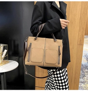Close-up of a khaki matte leather tote bag with functional front pockets and dual handles