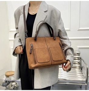 Close-up of brown matte tote bag with dual zipper pockets and adjustable shoulder strap