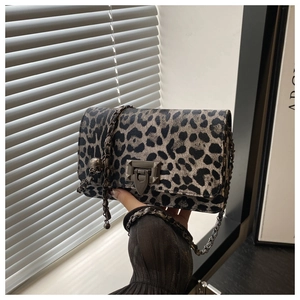 Detail of leopard print bag featuring a vintage metal buckle and leather chain strap