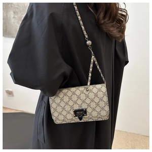 Fashionable crossbody bag with clover pattern and silver chain on minimalist model