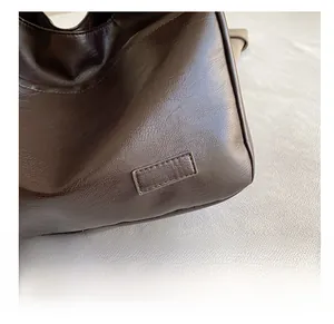 Detailed macro view of dark brown faux leather tote with textured litchi grain and stitching