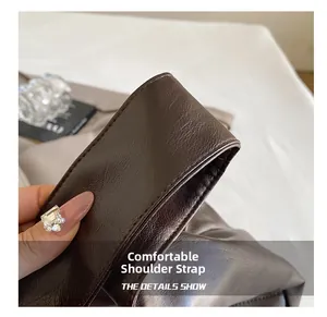 Detail showing the lychee grain leather strap and precise stitching of the brown tote bag