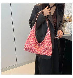 Borsa hobo rosa con motivi a cuore indossata da una modella in blazer di pelle marrone
