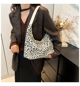 Borsa tote con stampa leopardata e ampia tracolla bianca indossata da una modella