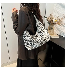 Vista laterale di una borsa hobo con stampa leopardata bianca indossata da una modella