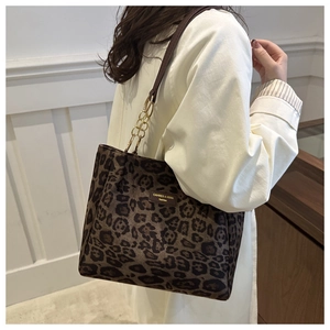 Detail of leopard print suede tote bag with leather straps and gold chain accents