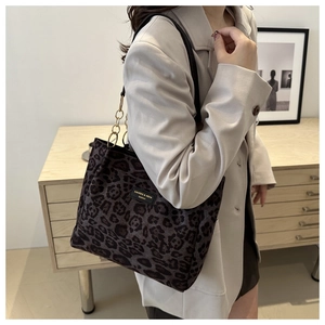 Detail of leopard print tote bag with gold chain strap on model in beige blazer