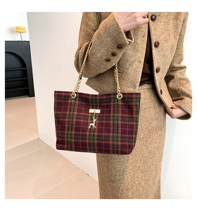 Detail of winter plaid tote bag with golden chain strap and deer charm ornament