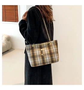 Détail d'un sac cabas en laine à carreaux avec bandoulière cuir et breloque cerf doré