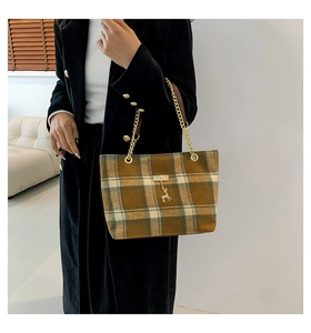 Détail du sac cabas en laine à carreaux avec chaîne dorée et breloque cerf sur manteau