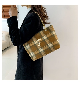 Detail of wool tote bag with classic brown plaid pattern and gold deer charm chain