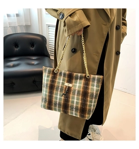 Detail of plaid tote bag featuring golden chain straps and a signature deer charm