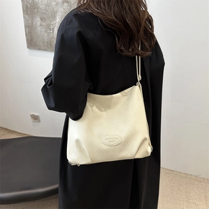 Minimalist beige textured leather hobo tote bag for women shown as worn on shoulder