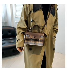Close-up of vintage plaid wool handbag with leather flap styled on khaki trench coat
