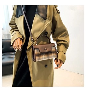 Detail of vintage PU leather and plaid wool small handbag worn with a trench coat