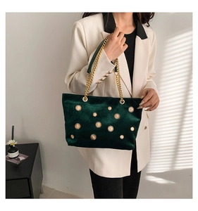 Sac cabas en velours vert foncé avec boucles soleil dorées porté par un mannequin