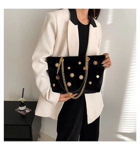 Détail du sac cabas en velours noir avec accents soleil dorés et bandoulière chaîne