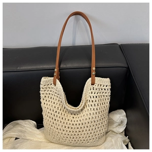 Detail of woven mesh shoulder bag with brown leather handles and gold metal rivets