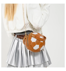 Detail shot of a stylish soccer-shaped crossbody bag with gold chain strap on a model