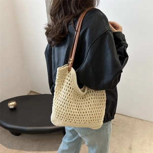 Beige hollow crochet tote bag with brown faux leather straps shown on a model's shoulder