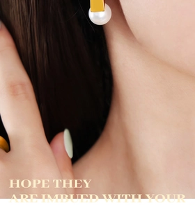 Detail of elegant gold rectangular pearl earrings and matching ring on a model