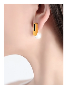 Detail of vintage gold earrings with faux pearls and black inlay on model ear