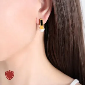 Vintage stainless steel pearl earrings featuring a geometric gold frame and black inlay