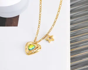 Dettaglio della collana d'oro con ciondolo a cuore in gemma verde sfumata e stella su catena