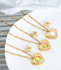 Dettaglio di ciondoli a cuore con cristalli colorati e stelle su collane d'oro
